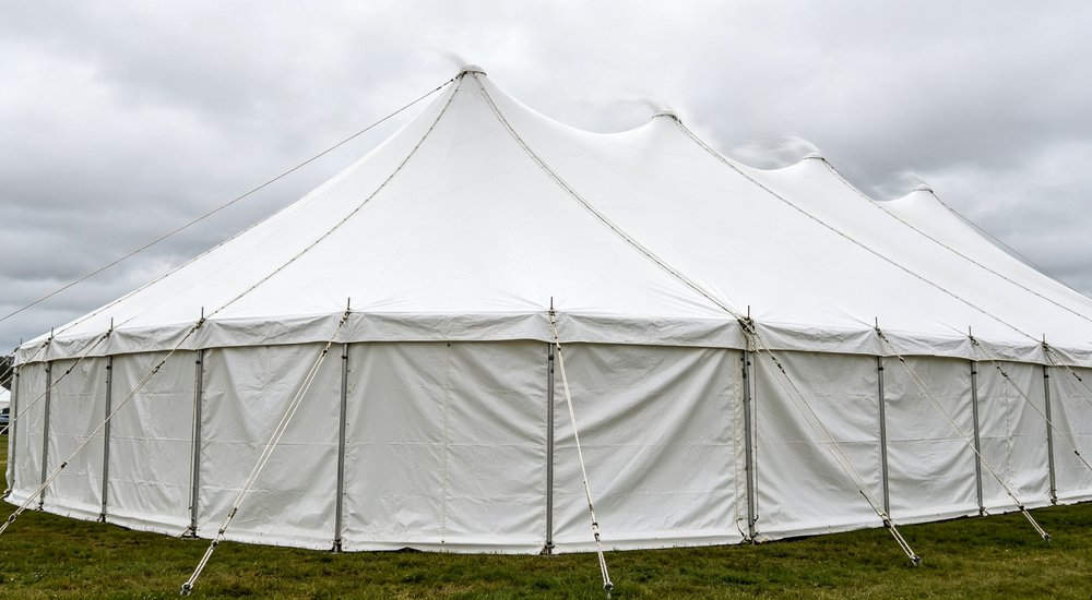 Air beam tent in strong wind with guy ropes, wind resistance test, green grass red and white inflatable emergency shelter for disaster relief operations