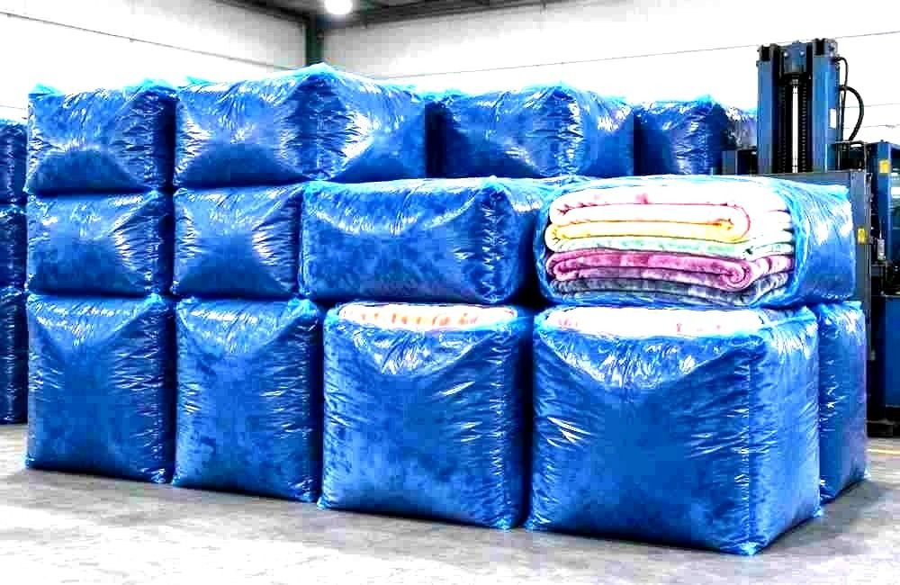 Compressed blanket bales stacked on pallets before dispatch, showing pre-positioning relief stock and packing for storm logistics by ocean freight